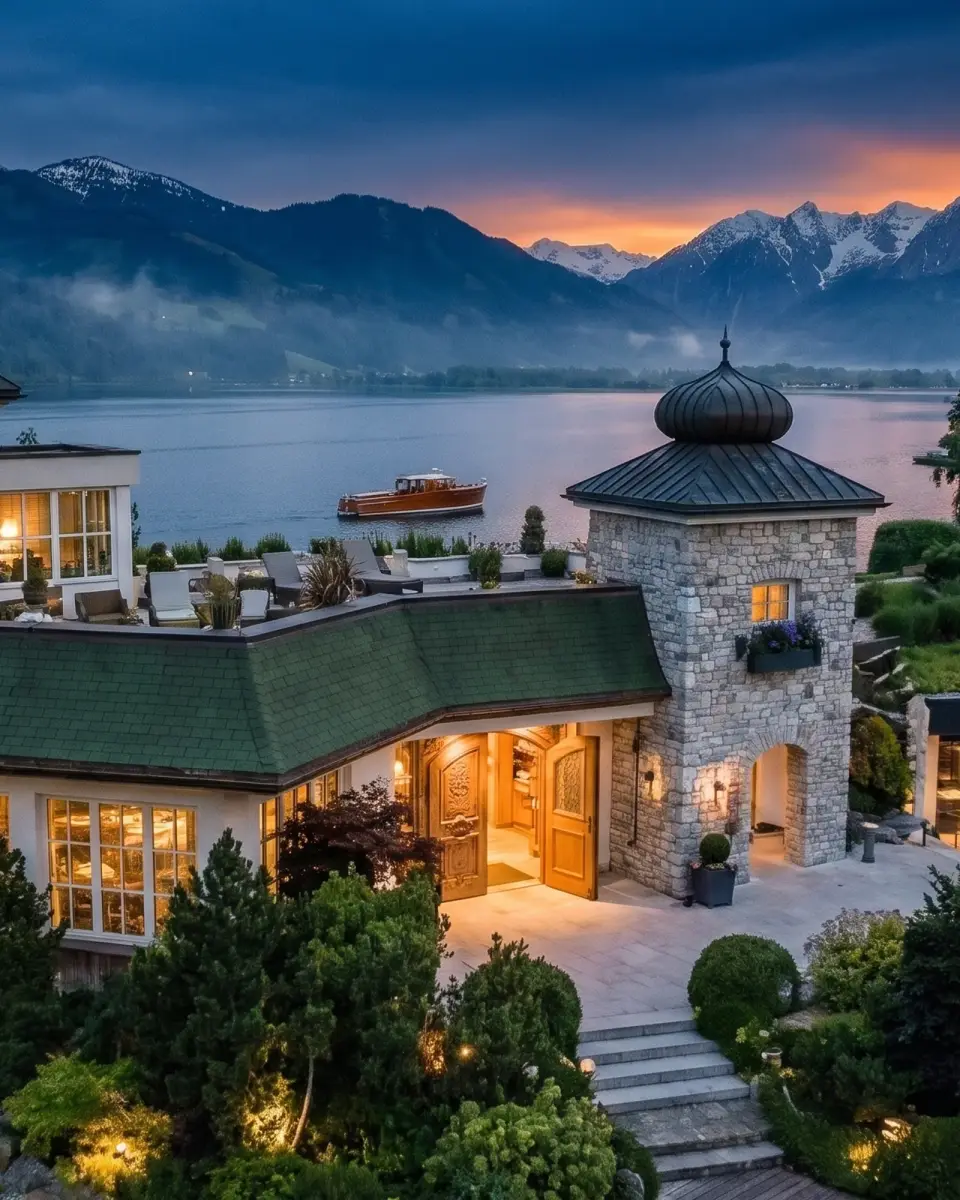 The arrival court from above at sunset, the doors open under the stone tower and a launch out on the lake