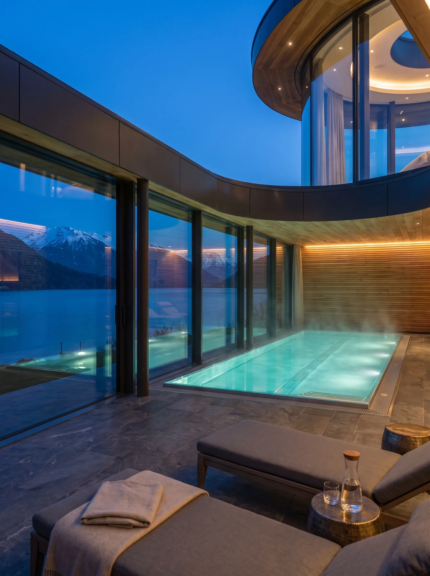 The indoor pool at The Meridian, lit through a wall of glass facing the lake and mountains